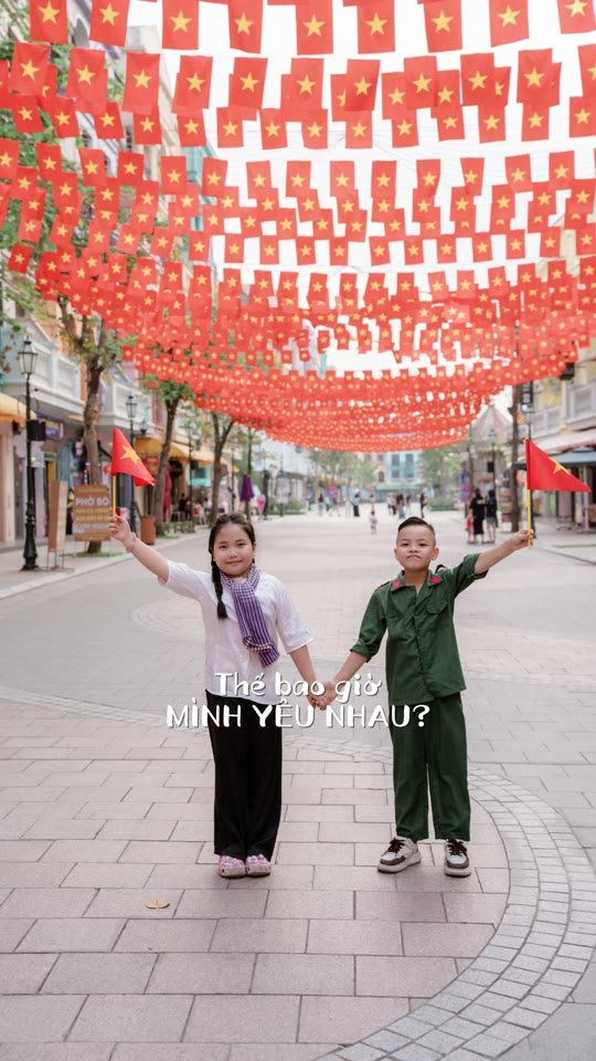 Hai bé áo lính nắm tay giữa phố cờ hoa — đáng yêu nhất mùa 2/9 năm nay